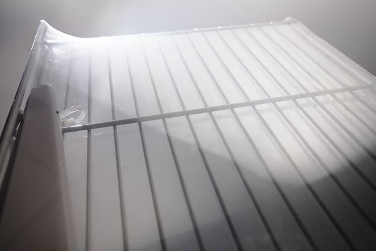 Empty refrigerator shelf in bright lighting.